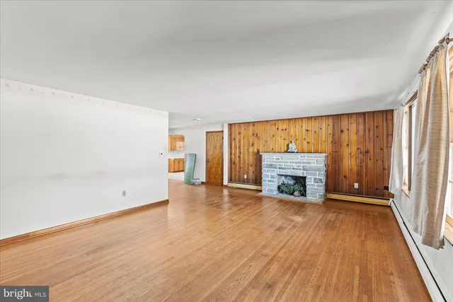 an empty room with wooden floor fireplace and windows