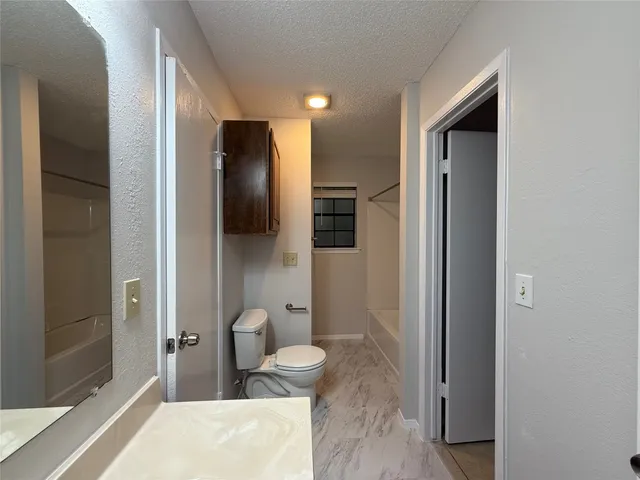 a bathroom with a granite countertop sink a toilet and shower