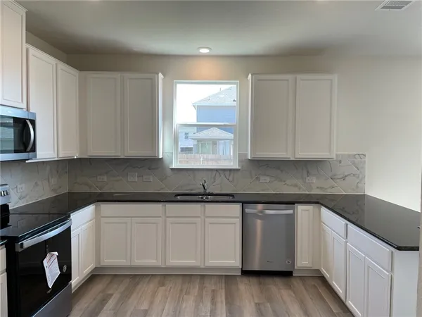 a kitchen with stainless steel appliances granite countertop white cabinets sink and dishwasher
