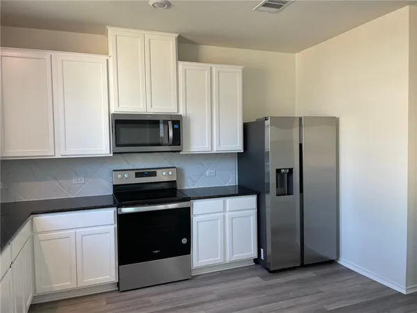 a kitchen with white cabinets and stainless steel appliances