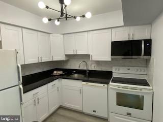 a kitchen with granite countertop white cabinets and black appliances