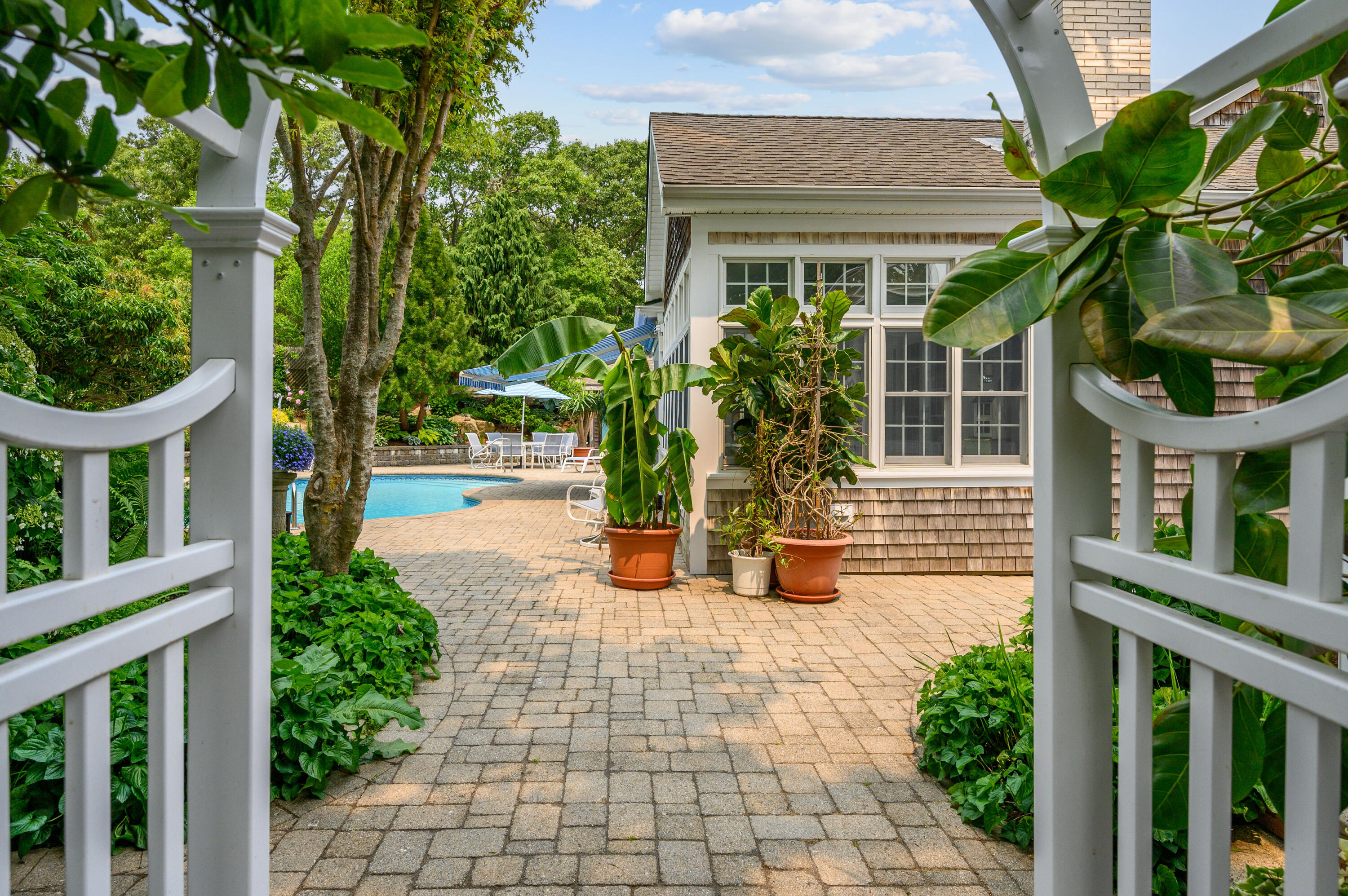 256 Pleasant Bay Road Harwich, MA 02645 - Photo 45 of 71 a view of a house with potted plants and a bench in a yard