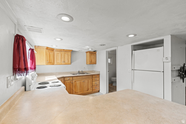 180 South 300 East Logan, UT 84321 - Photo 23 of 35 Kitchen with white appliances, light countertops, recessed lighting, a peninsula, and a textured ceiling