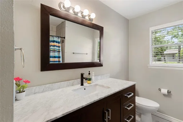 a bathroom with a sink vanity granite toilet and a mirror