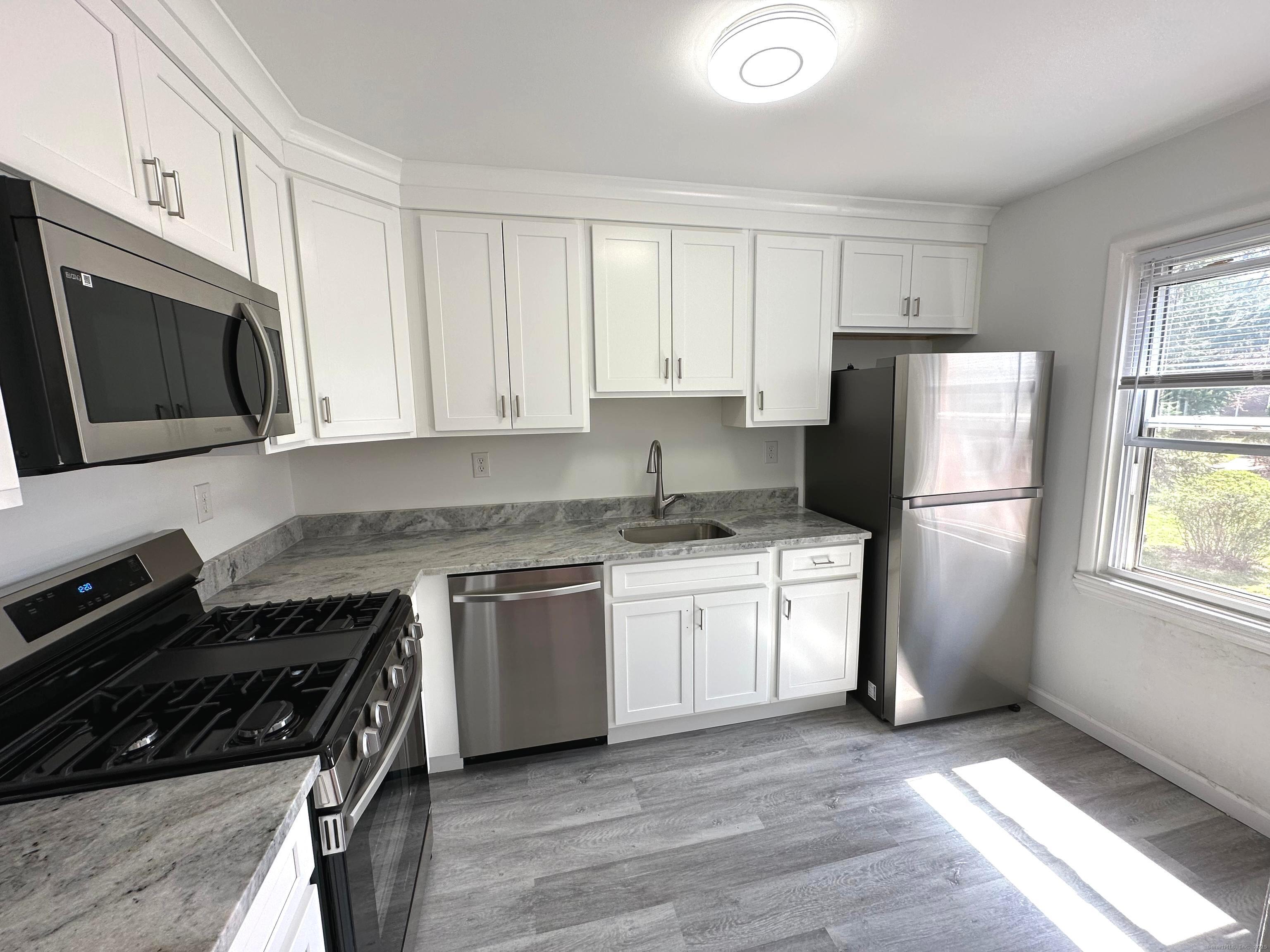 a kitchen with stainless steel appliances granite countertop a stove a refrigerator a sink dishwasher and a refrigerator