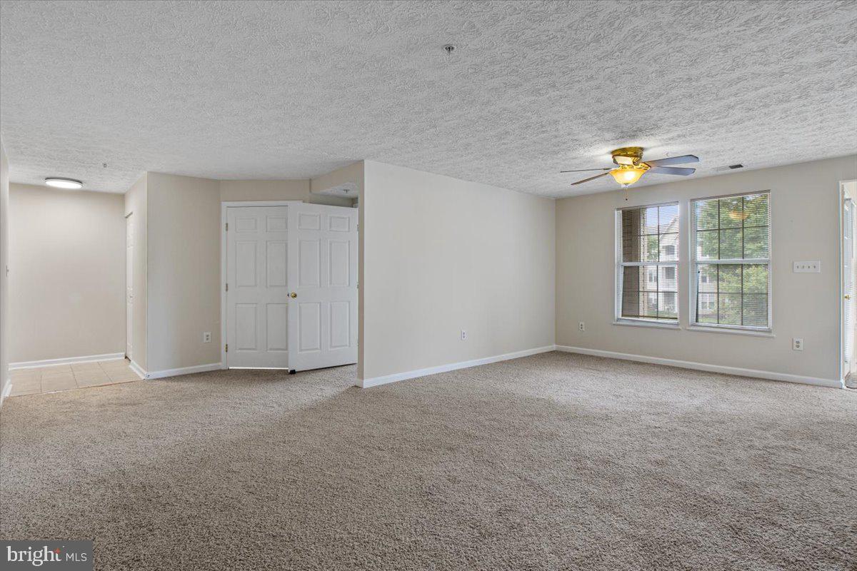2445 Blue Spring Court, Unit 103 Odenton, MD 21113 - Photo 6 of 31 an empty room with windows and ceiling fan