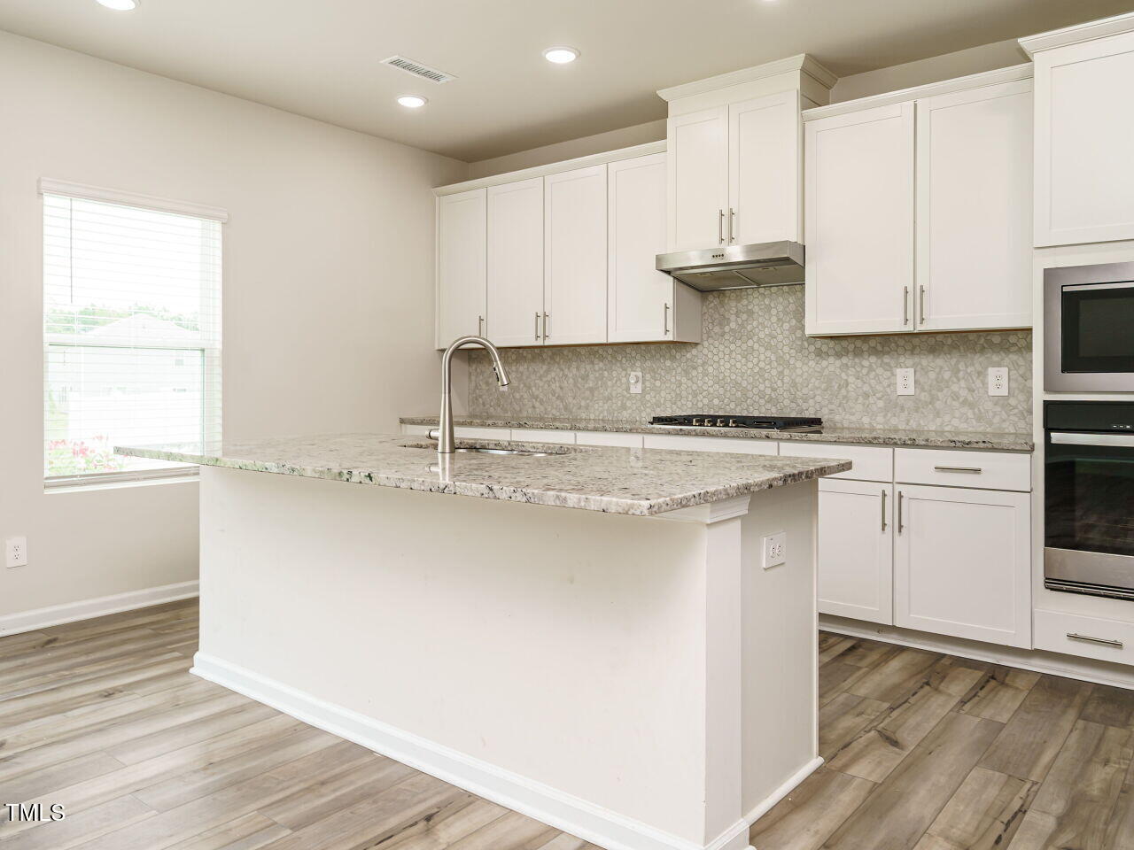 792 Riguard Way Wendell, NC 27591 - Photo 6 of 46 a kitchen with stainless steel appliances granite countertop a sink a stove and white cabinets with wooden floor