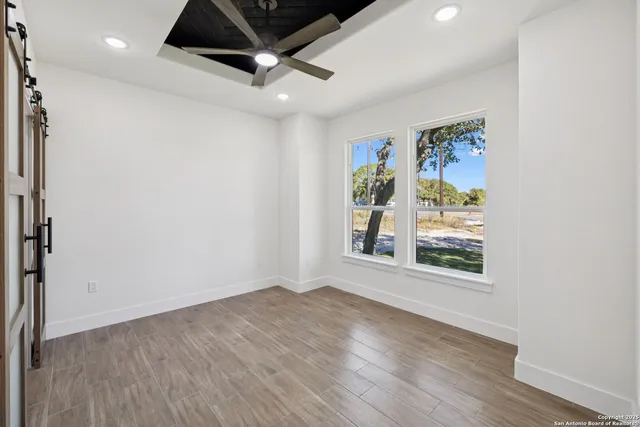 an empty room with wooden floor and windows