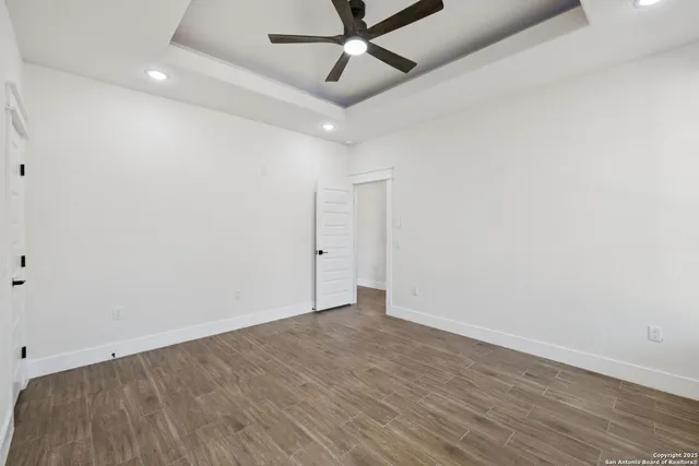 an empty room with a ceiling fan and wooden floor