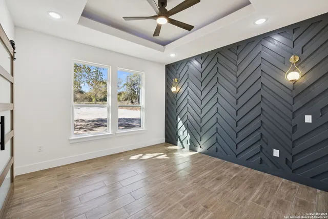 a view of an empty room with a window and wooden floor