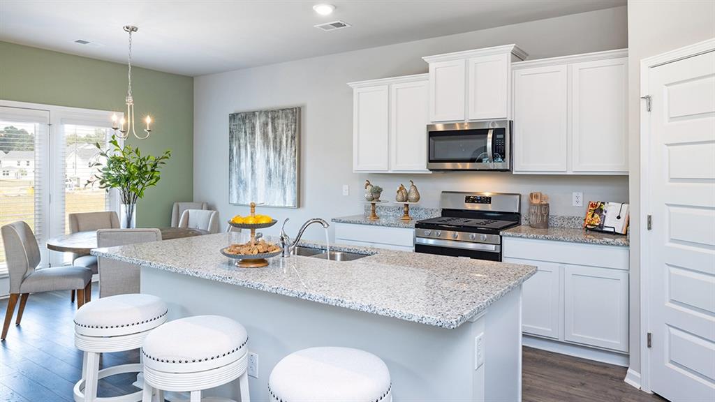 1910 Van Alen Court Dacula, GA 30019 - Photo 34 of 64 a kitchen with a sink a stove and chairs