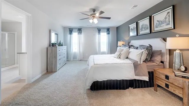 a bedroom with a bed and a lamp on dresser next to a window
