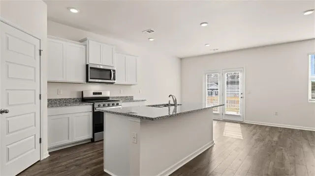 a kitchen with granite countertop a stove sink and microwave