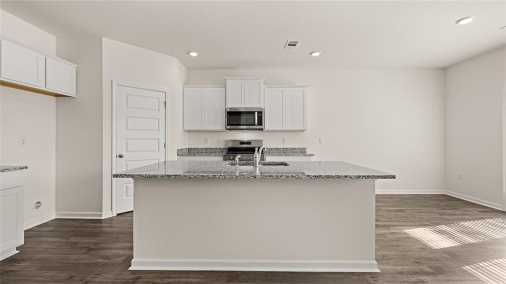 1910 Van Alen Court Dacula, GA 30019 - Photo 7 of 64 a kitchen with stainless steel appliances granite countertop a sink a stove a microwave a sink and white cabinets