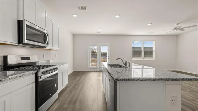 an empty room with windows and chandelier fan