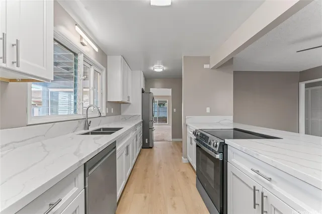 a large kitchen with granite countertop a sink and cabinets with wooden floor