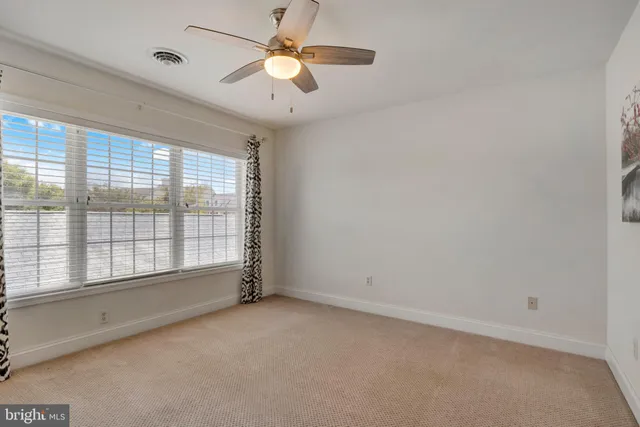 an empty room with chandelier fan and windows