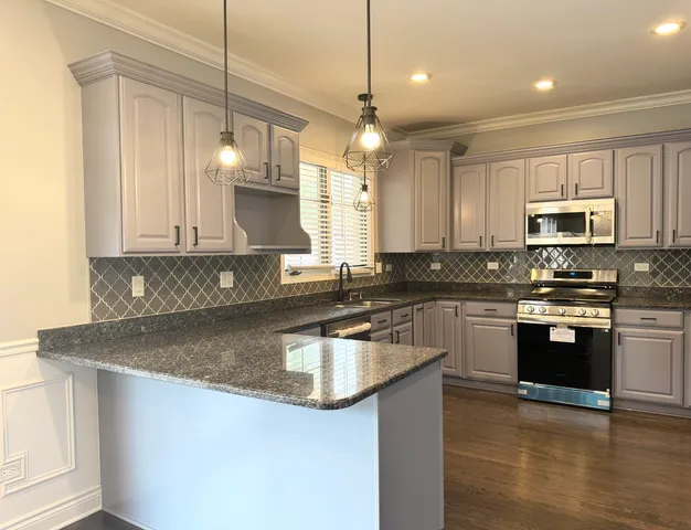a kitchen with kitchen island granite countertop a sink window and stainless steel appliances