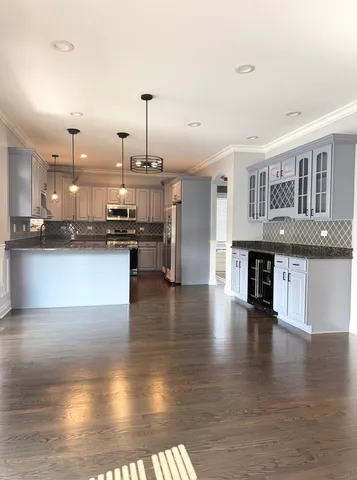 a large kitchen with stainless steel appliances granite countertop a stove and a wooden floors