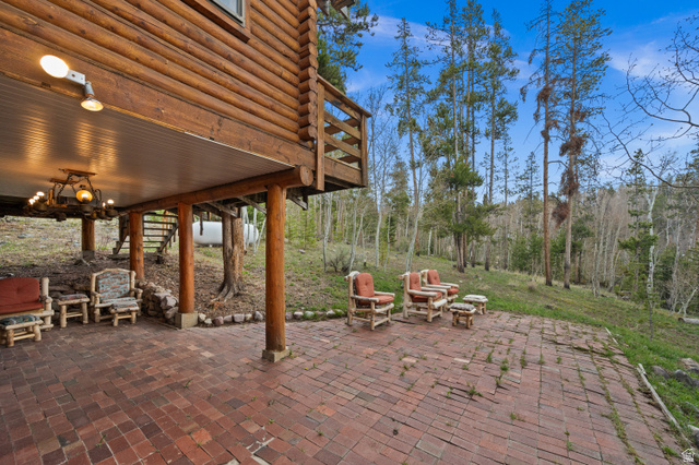 4725 Pine Ridge Road Evanston, UT 82930 - Photo 58 of 82 Expansive brick patio featuring a covered outdoor area with a rustic chandelier and a log cabin exterior