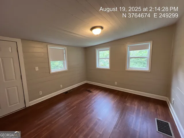 an empty room with wooden floor fan and windows