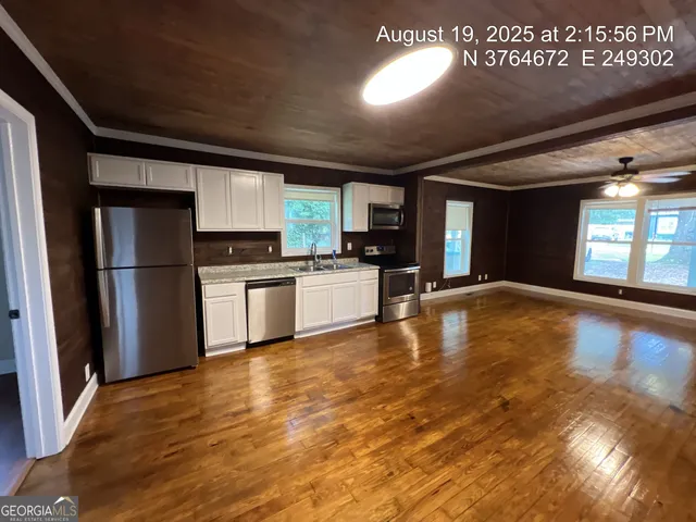 a kitchen with stainless steel appliances granite countertop a refrigerator a stove and a sink with wooden floor