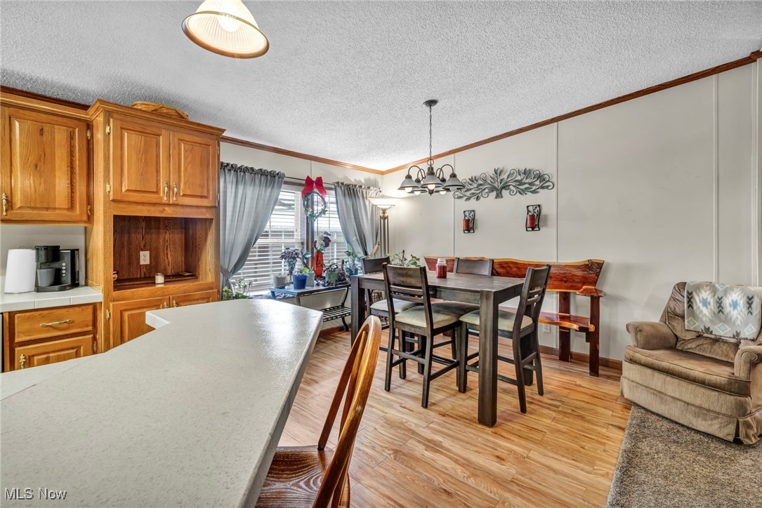 27202 Cook Road, Unit 95 Olmsted Falls, OH 44138 - Photo 13 of 46 Dining area with crown molding, light wood finished floors, a textured ceiling, a chandelier, and vaulted ceiling