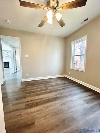 an empty room with wooden floor chandelier fan and windows
