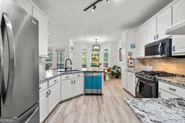 a kitchen with stainless steel appliances granite countertop a stove top oven a sink dishwasher a refrigerator and a oven with wooden floor