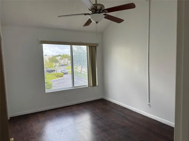 an empty room with wooden floor fan and windows