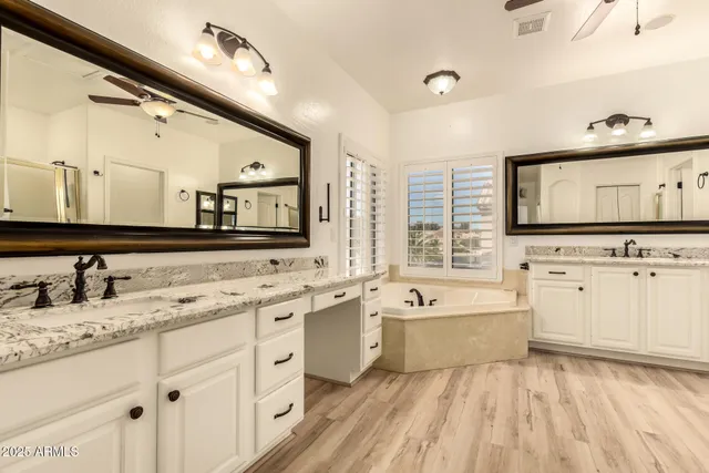a spacious bathroom with a double vanity sink mirror and bathtub