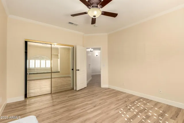 a view of empty room with wooden floor and fan