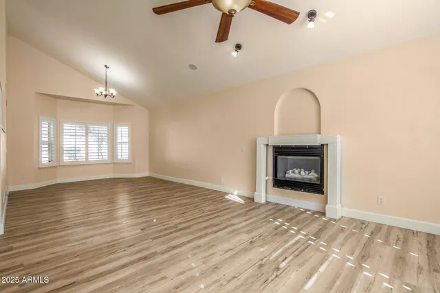 an empty room with wooden floor fireplace and windows