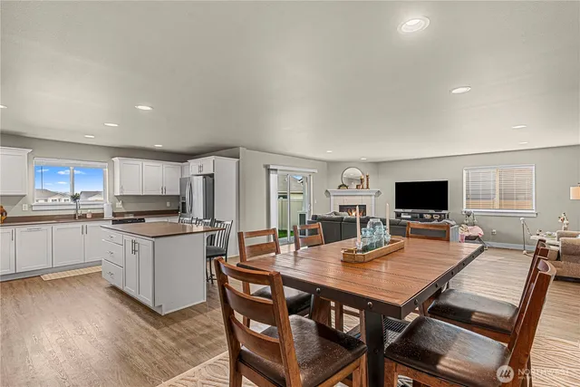 a living room with stainless steel appliances furniture a flat screen tv and a dining table
