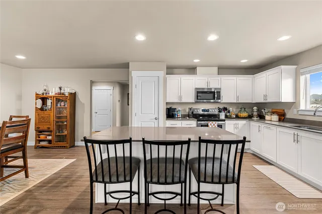 a kitchen with stainless steel appliances granite countertop a stove top oven a sink a dining table and chairs