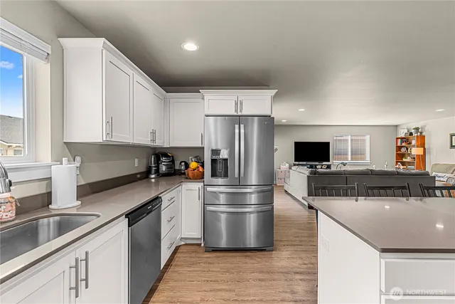 a kitchen with stainless steel appliances a refrigerator sink and white cabinets