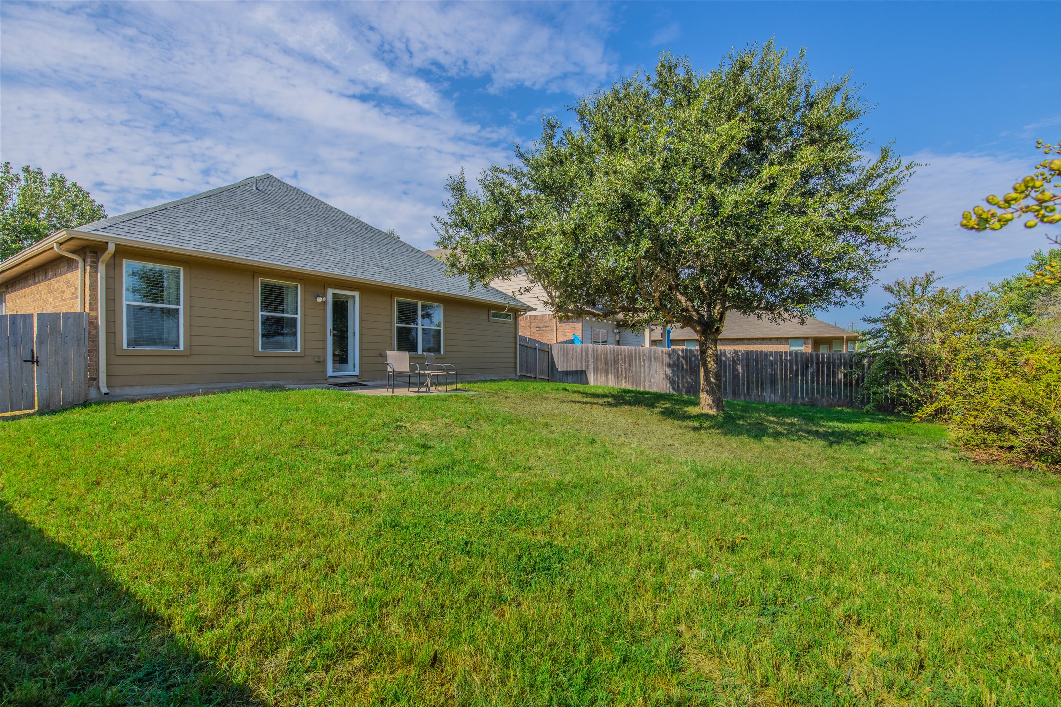 1089 Hot Spring Valley Buda, TX 78610 - Photo 23 of 26 A spacious grassy lawn bordered by mature trees and a sturdy wood fence.