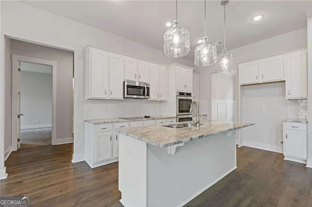 a kitchen with kitchen island granite countertop a sink cabinets and stainless steel appliances