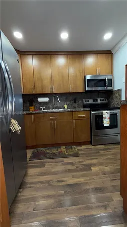 a view of a kitchen with stainless steel appliances wooden floor and a refrigerator