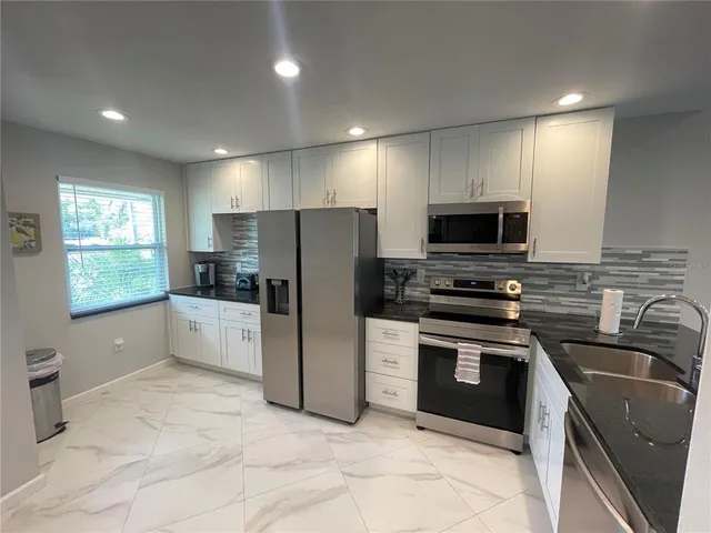 a kitchen with a sink a counter top space stainless steel appliances and cabinets