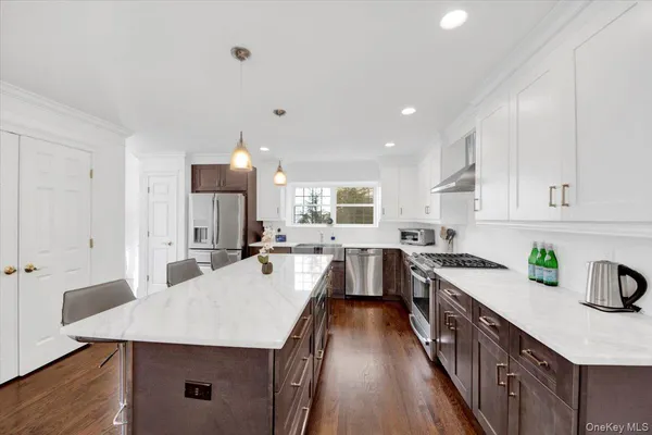 a kitchen with stainless steel appliances a kitchen island hardwood floor sink stove and wooden cabinets