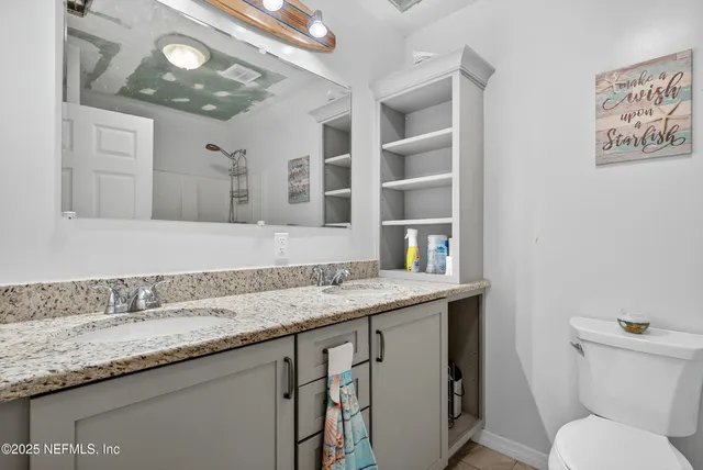 a bathroom with a granite countertop toilet sink and mirror