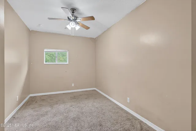 an empty room with a window and a ceiling fan