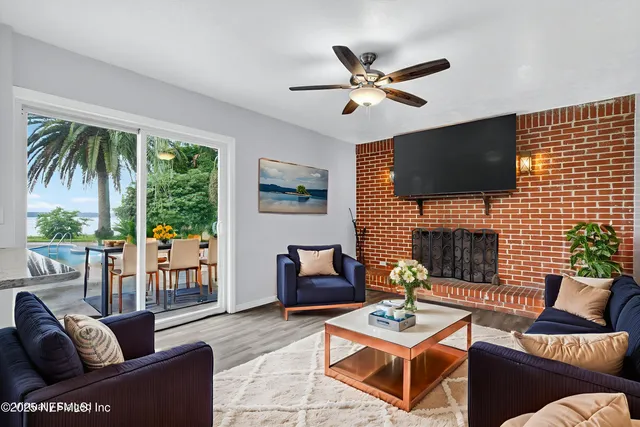 a living room with furniture a fireplace a flat screen tv and a large window