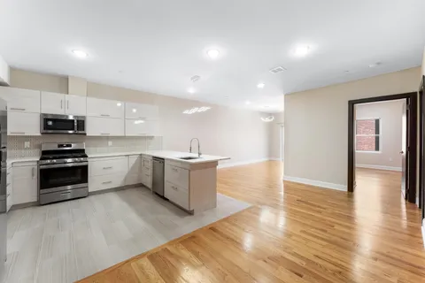 a large kitchen with a large counter top a sink stainless steel appliances and cabinets