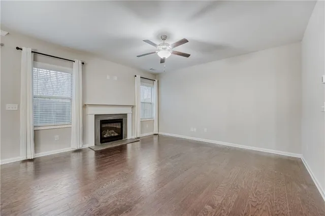 an empty room with wooden floor a chandelier fan and a fireplace