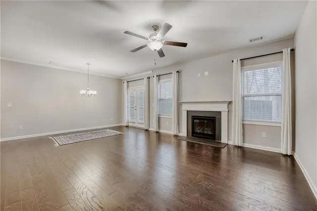 a view of an empty room with wooden floor fireplace and a window