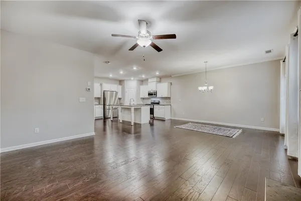 a view of an empty room with wooden floor and a ceiling fan