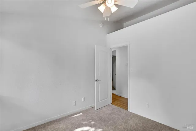 an empty room with windows and ceiling fan