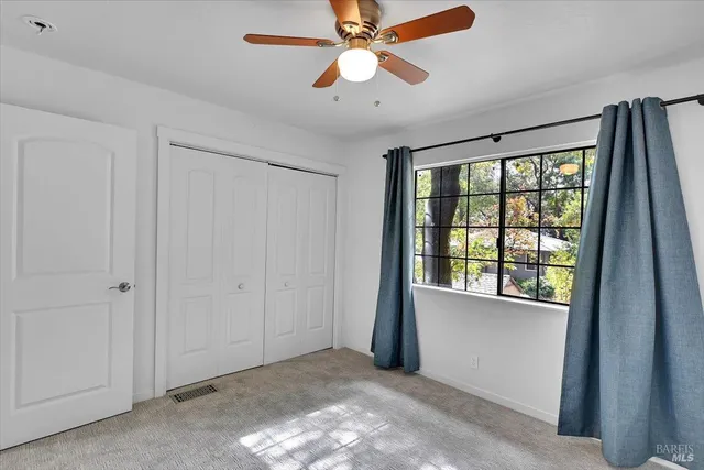 an empty room with closet and a chandelier fan